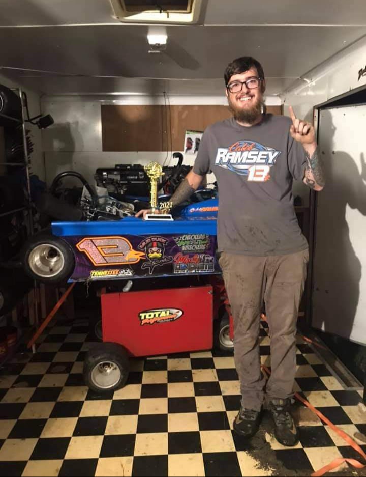 Caleb Ramsey standing beside his #13R kart